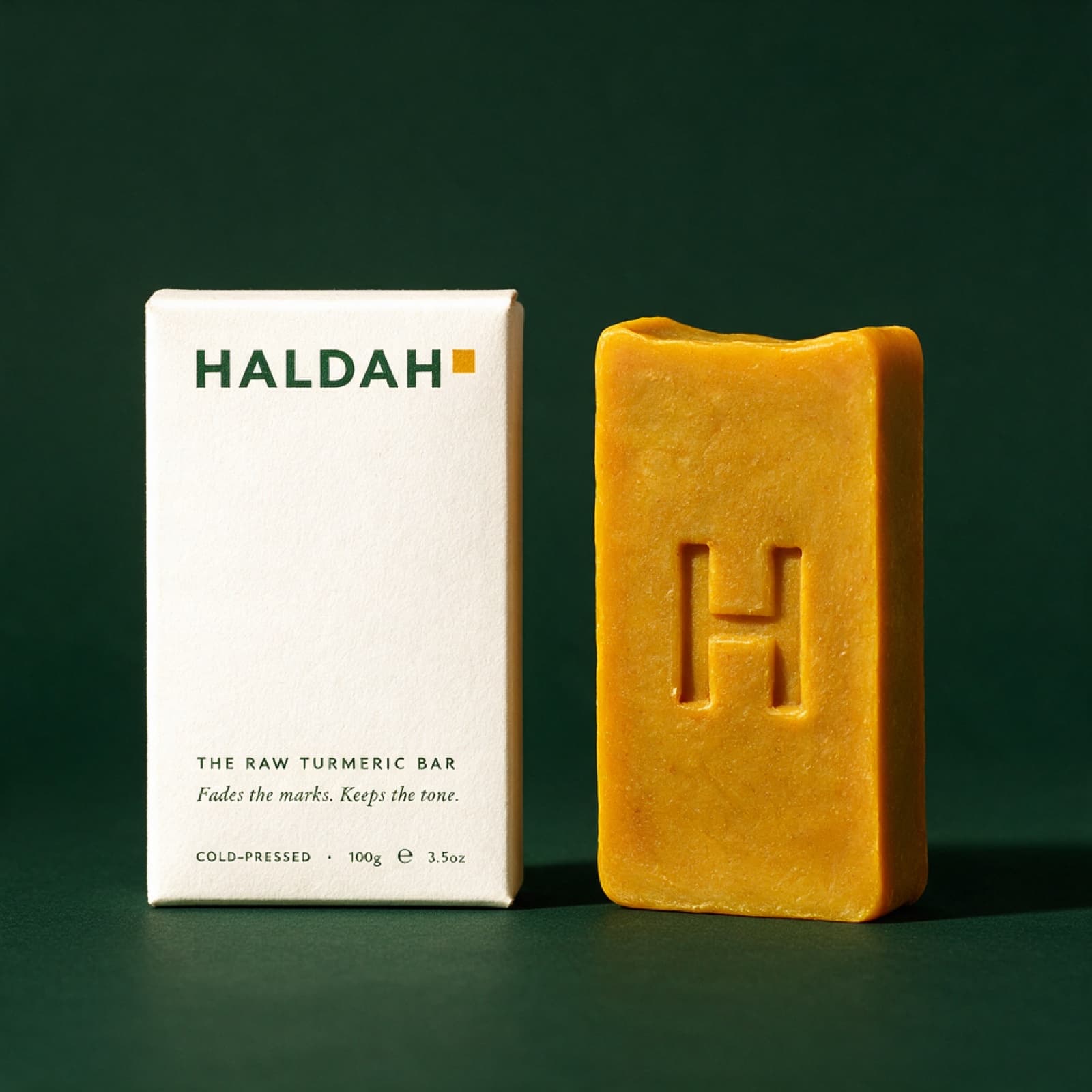 The Raw Turmeric Bar beside its box, the H pressed into the bar