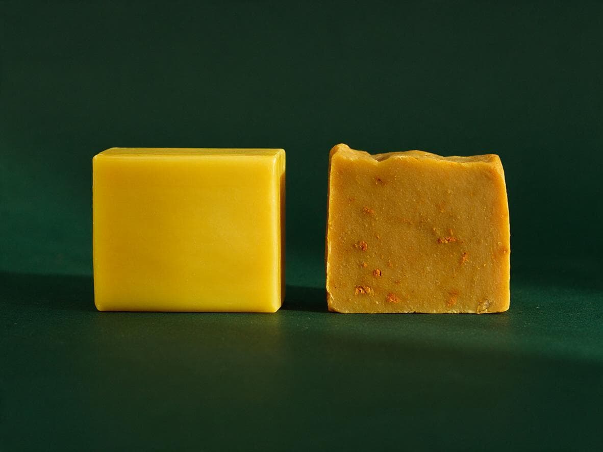 A glossy uniform yellow bar beside a matte hand-cut bar flecked with turmeric root